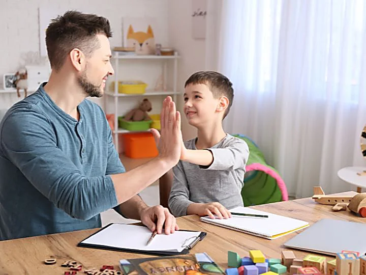 Educatore e bambino si danno il cinque durante un incontro in studio